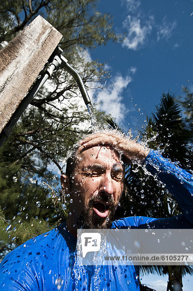 Man rinsing off under an outdoor shower  Cook Islands.