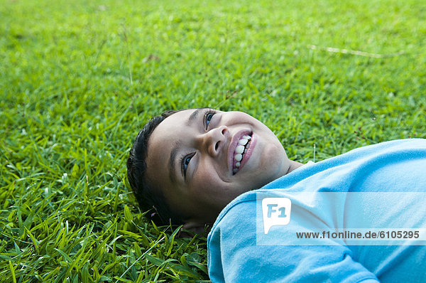 Boy laying in grass smiling  Cook Islands.