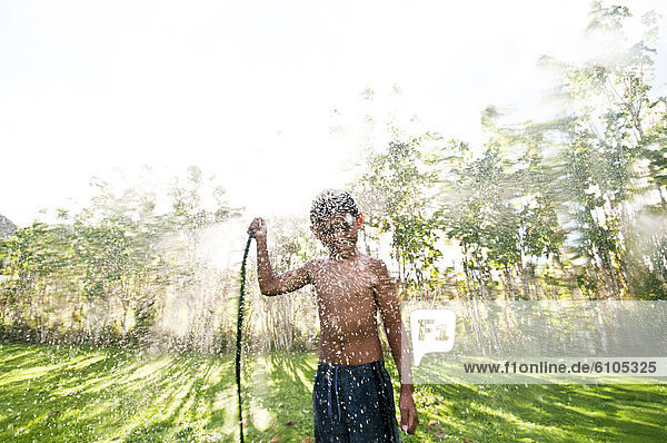 Boy spraying water from a hose  Cook Islands.