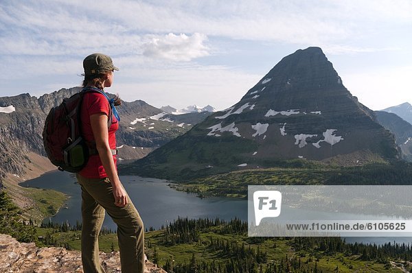 A young female hiker looks out over Hidden Lake and Bear Hat Mountain in Glacier National Park  Montana.
