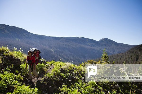 a woman hikes above tree line on Williams Creek Trail (trail number 587) while carrying her son in her backpack.