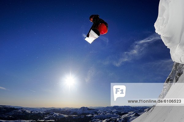 A snowboarder soaring in the air at sunrise in the Sierra Nevada mountains near Lake Tahoe  California.