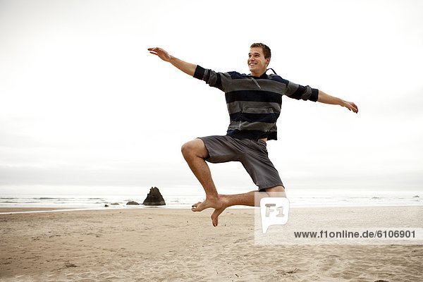 Male doing a heel click on a beach.