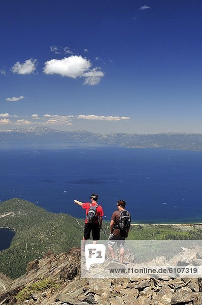 Two male hikers stand on the summit of Mount Tallac looking out over Lake Tahoe  California.