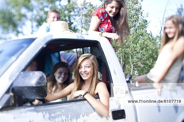 A teenage girl drives her friends in a pick up truck as they enjoy a Summer afternoon.