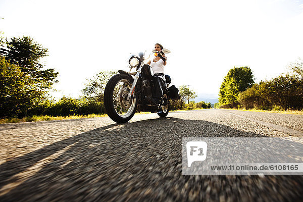 A sexy woman riding her motorcycle on a smooth country road in Idaho.