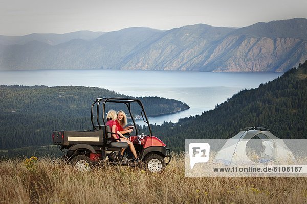 Two women laugh and smile while driving a off road ATV to their camp site in Idaho.