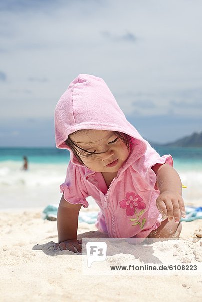 A baby crawling in the sand at the beach in Waimanalo  Hawaii.