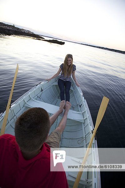 A young man and girl enjoy that sunset in a Peapod dinghy along the coast of Maine.