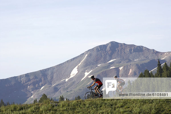 Two cyclists riding at the crest of a mountain pass near Vail  Colorado.