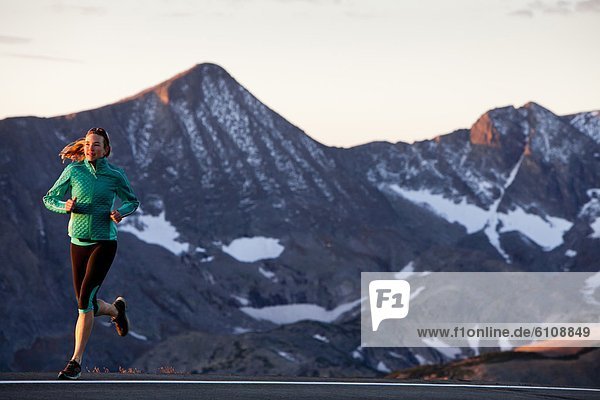 An athletic woman runs along Trail Ridge Road (12 183 feet) near its apex at sunrise  Rocky Mountain National Park  Colorado.