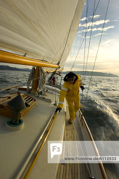 Man walks on the deck of a sailing yacht.