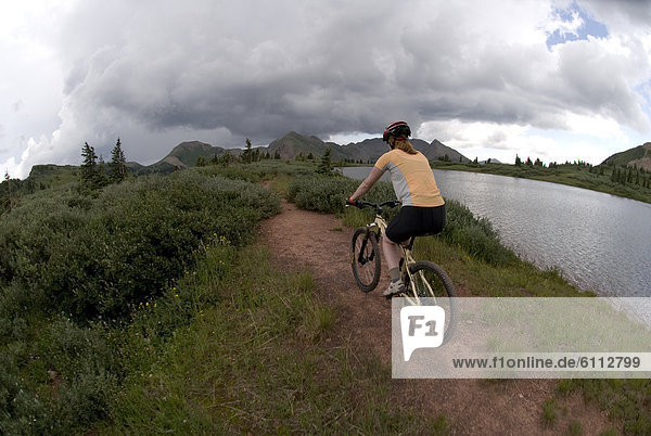 Woman mountain bikes along Lake.