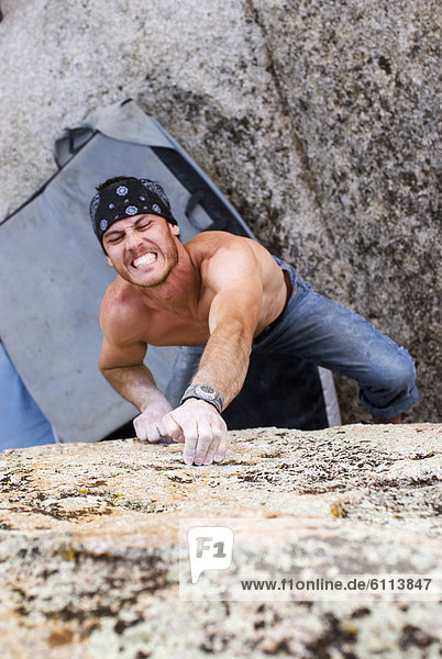 Young man rockclimbing granite boulders in Bishop  California