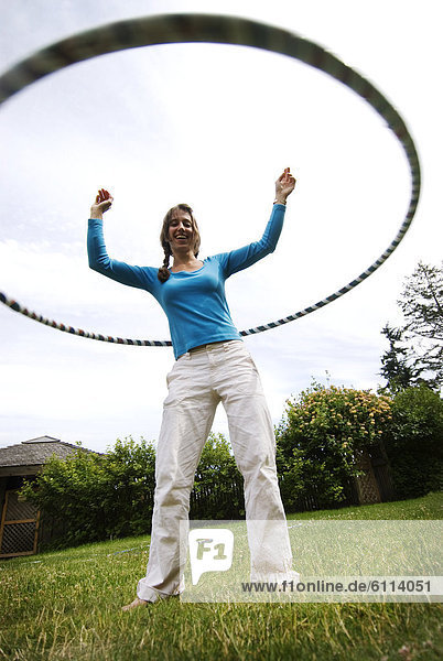 A young woman hula hoops on a green lawn in British Columbia  Canada.