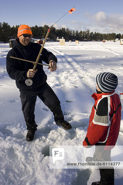 A man teaches a boy how to ice fish on Maine Lake in North Waterboro  Maine.