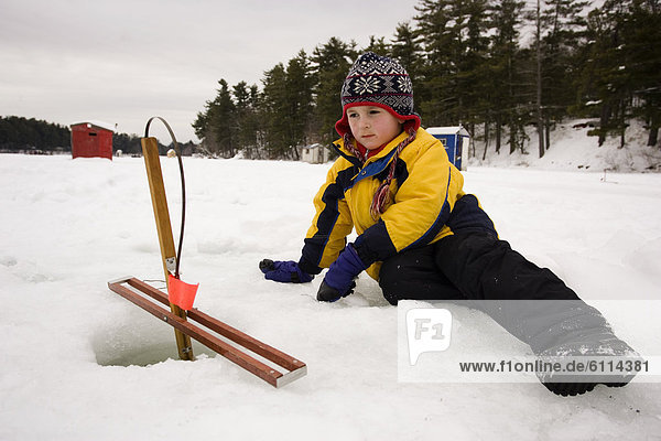 A boy checks traps  while ice fishing on Maine Lake in North Waterboro  Maine.