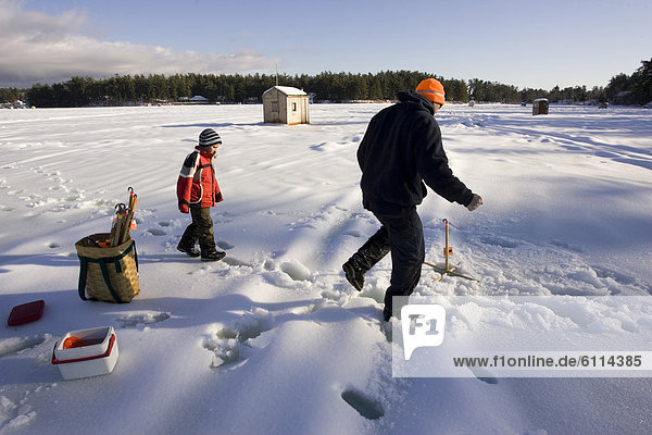 A man teaches a boy how to ice fish on Maine Lake in North Waterboro  Maine.