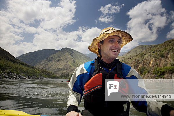 A smiling man floats on a raft down a river in Idaho  USA.