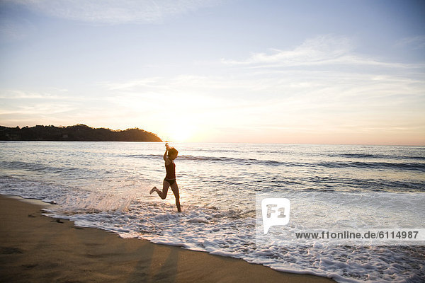 A young woman runs in the surf at sunset in Sayulita  Mexico.