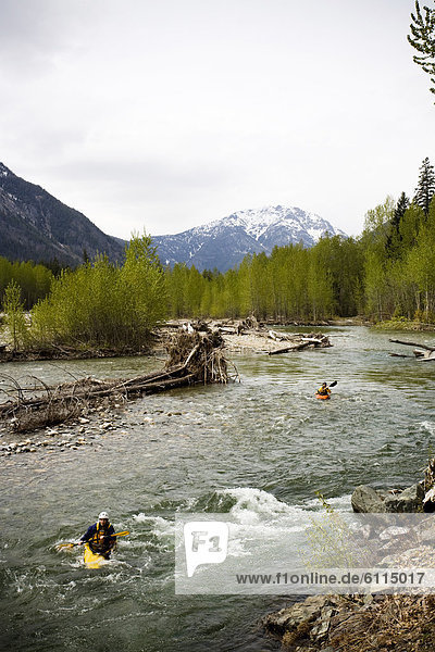 Two kayakers enjoy calm whitewater on a remote river in Washington.