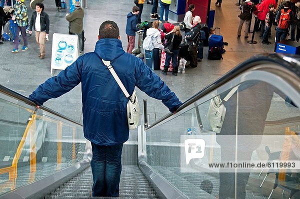 young man on escalator connecting Cointrin Airport with train station  Geneva  Switzerland