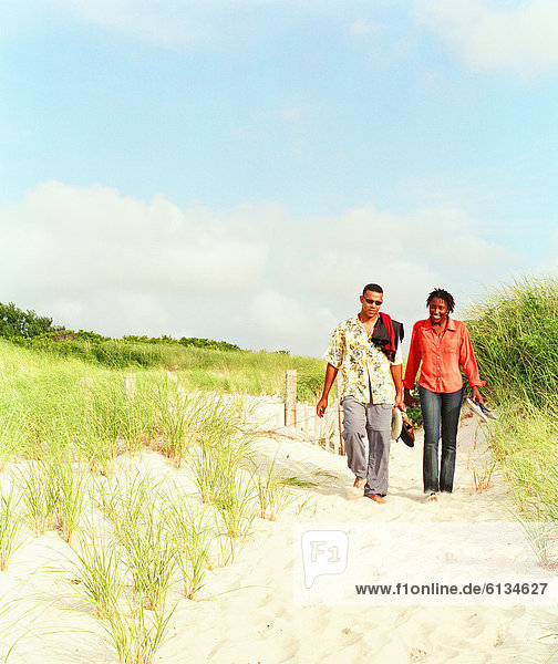 Young couple walking bare feet in sand