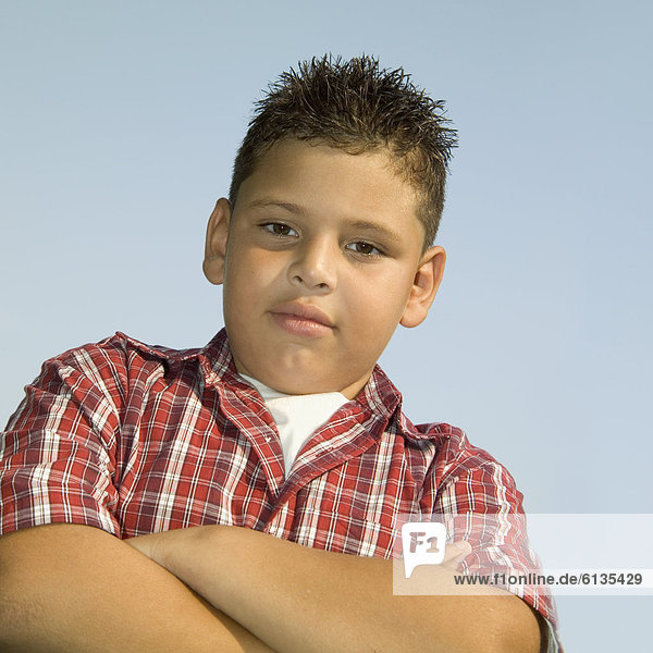 Low angle view of a young boy standing with his arms folded