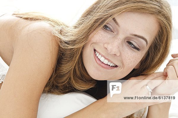 Smiling young woman lying in bed