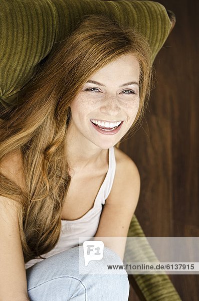 Happy young woman sitting in armchair