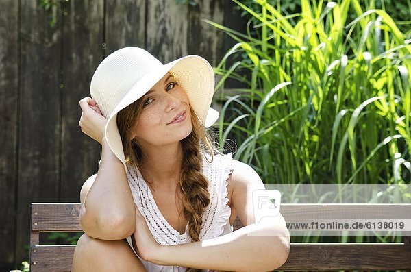 Smiling young woman sitting on bench  portrait