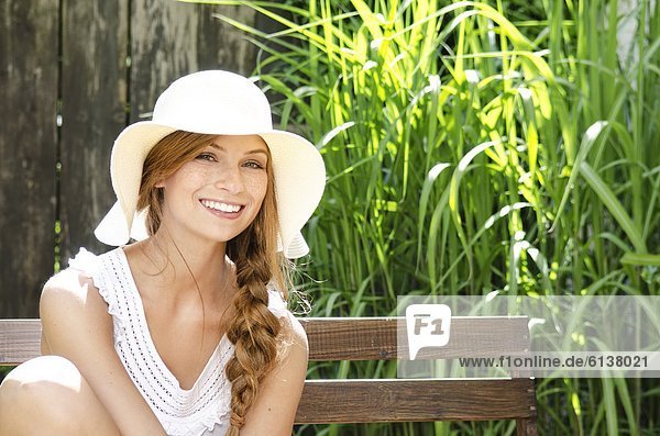 Smiling young woman sitting on bench  portrait