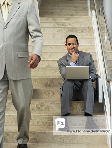 Businessman sitting on steps with laptop