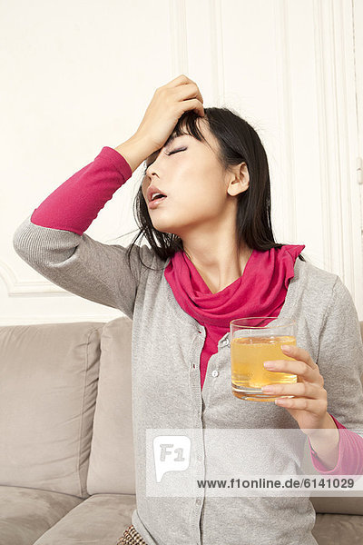 Frau trinkt Saft auf der Couch