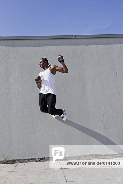 Man jumping against wall outdoors