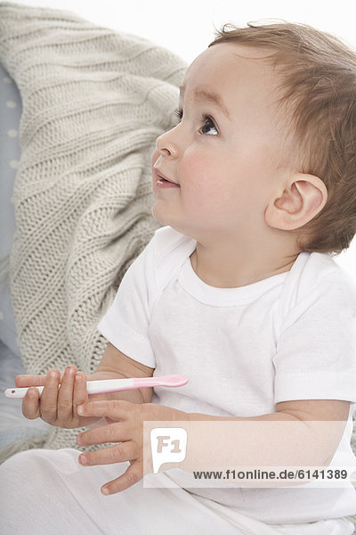 Lächelndes Baby beim Spielen mit dem Plastiklöffel