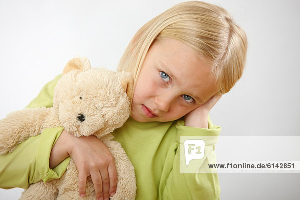 Girl with teddy covering ears