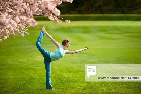 Frau in stehender Bogen-Yogastellung im Park