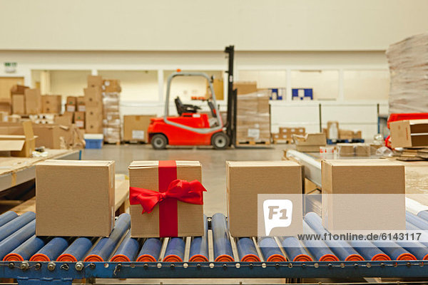 Cardboard box with red bow on conveyor belt