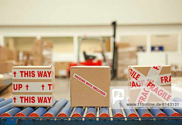 Three cardboard boxes with parcel tape on conveyor belt