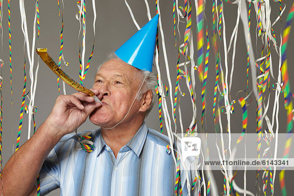 Senior Mann mit Partygebläse und Luftschlangen