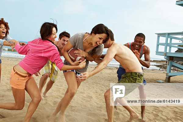 Friends on beach playing rugby