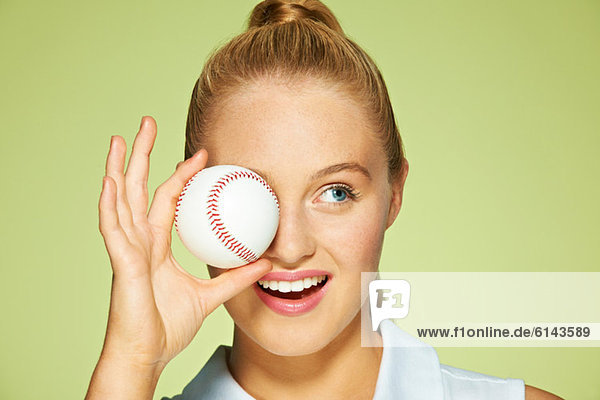 Junge Frau hält Baseball vor Augen