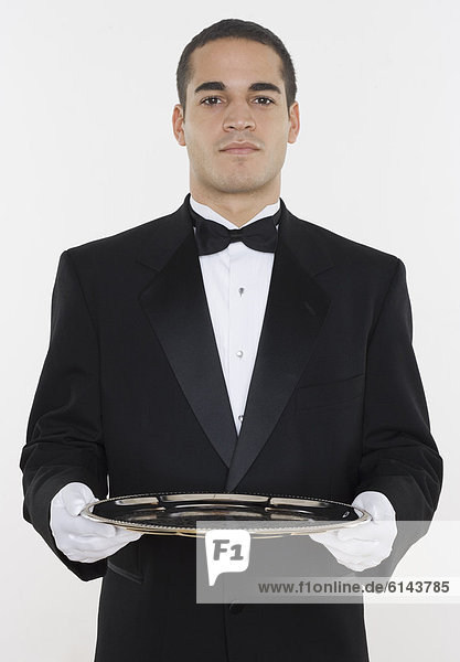 Portrait of male waiter holding tray