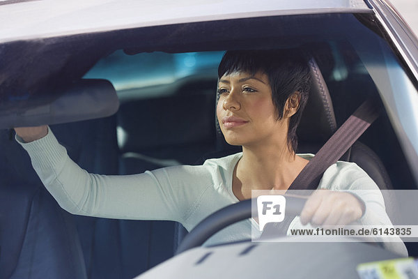 Woman adjusting rear view mirror in car