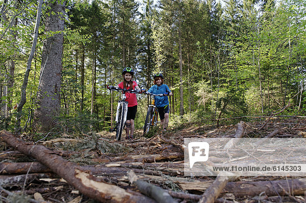 Children riding their bicycles  pushing their bikes across roots  mountain biking tour near Dietramszell  Toelzer Land region  Upper Bavaria  Bavaria  Germany  Europe