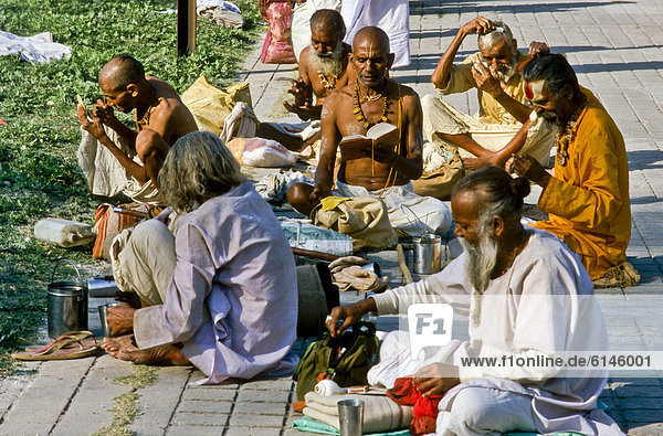Gruppe von Sadhus beim Auftragen der Tilakas  Segenszeichen auf der Stirn  während der morgendlichen Puja oder Pooja  Hardiwar  Indien  Asien