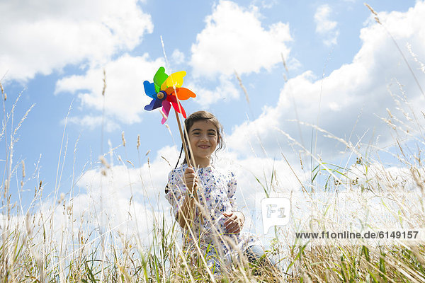 Girl with two paper windmills on a meadow