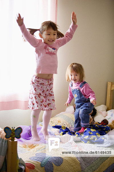 Two girls jumping on bed