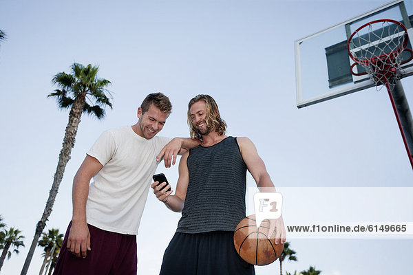 Caucasian basketball players looking at cell phone